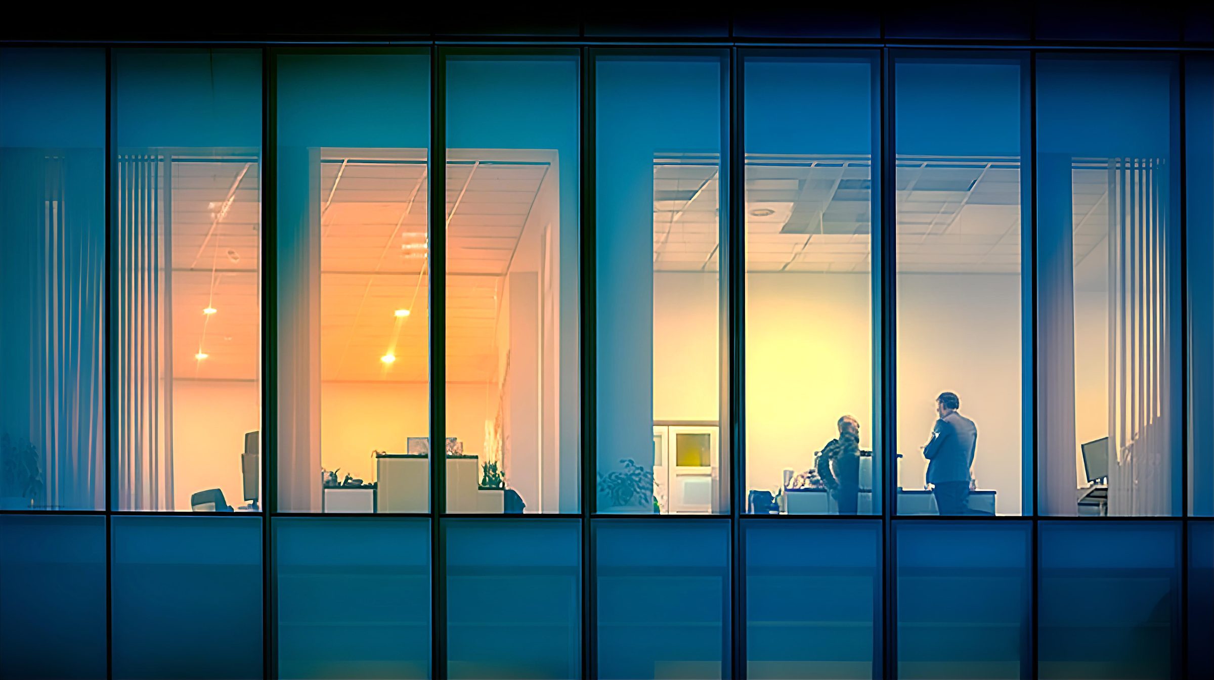 Offices lit at dusk seen through glass